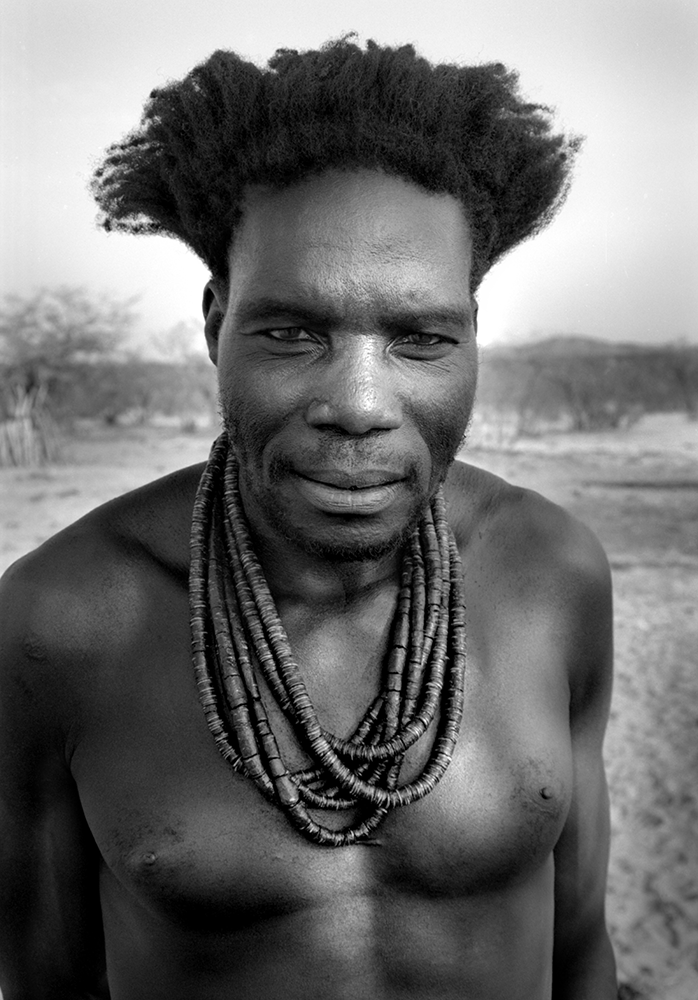 A portrait of a relative of Ukoruavi Tjambiru during a mourning ceremony at Embuende, where family members had gathered the cattle to be shared to mark the end of the mourning period. His hair and necklace are left untied as a sign of mourning.